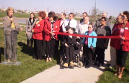 Mayor McCartt delivering a speech while (from left to right) Chandy Davis, (ED Amarillo) Amarillo Chamber of Commerce volunteers in Red Blazers, Larry Offerdahl, (back row) Robert Stack,(CEO/Pres. COI) Don Boyd, City Commissioner, (front row) Quinton Barton, John Wise, Tonya Duck, Ruben Olivarez, and other Chamber of Commerce volunteers waited to cut the ribbon.
