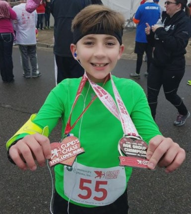 Logan shows off his medals at the 2018 Cupid’s Chase race in Paducah.