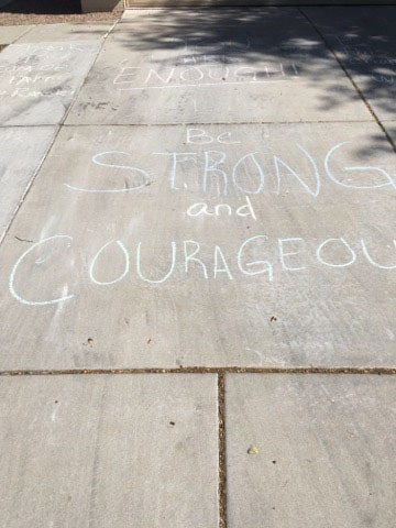 Be strong and courageous and other encouraging messages written with chalk on driveway.