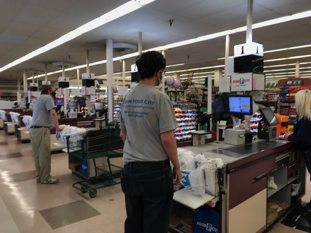Walker and Johnson working behind the registers at food city.