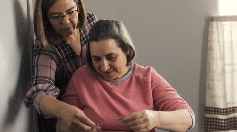 Individual with disabilities solving a puzzle with help from a Direct Support Professional