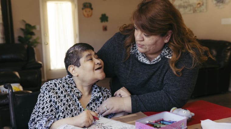 CommOp 3239 1 Individual with disabilities completing an activity book along with a Direct Support Professional
