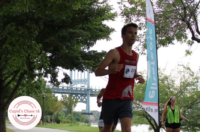 NYC Cupids Chase photo of one runner in foreground a few runners befind him and bridge in backround