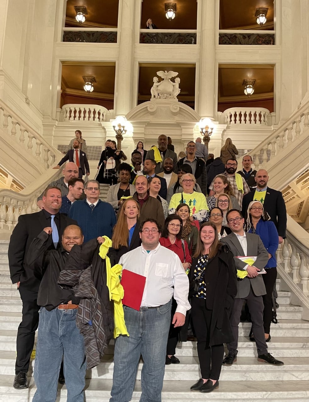 Community Options Inc. executive directors, regional directors, and the state director for Pennsylvania gathered on the steps inside the Harrisburg capitol building following the press conference for the advocacy of increased wages for direct support professionals. Several representatives from the state of Pennsylvania, family members, and executives from agencies that employ direct care workers spoke at the press conference on the need of better wages and more qualified staff to support adults with intellectual and developmental disabilities.