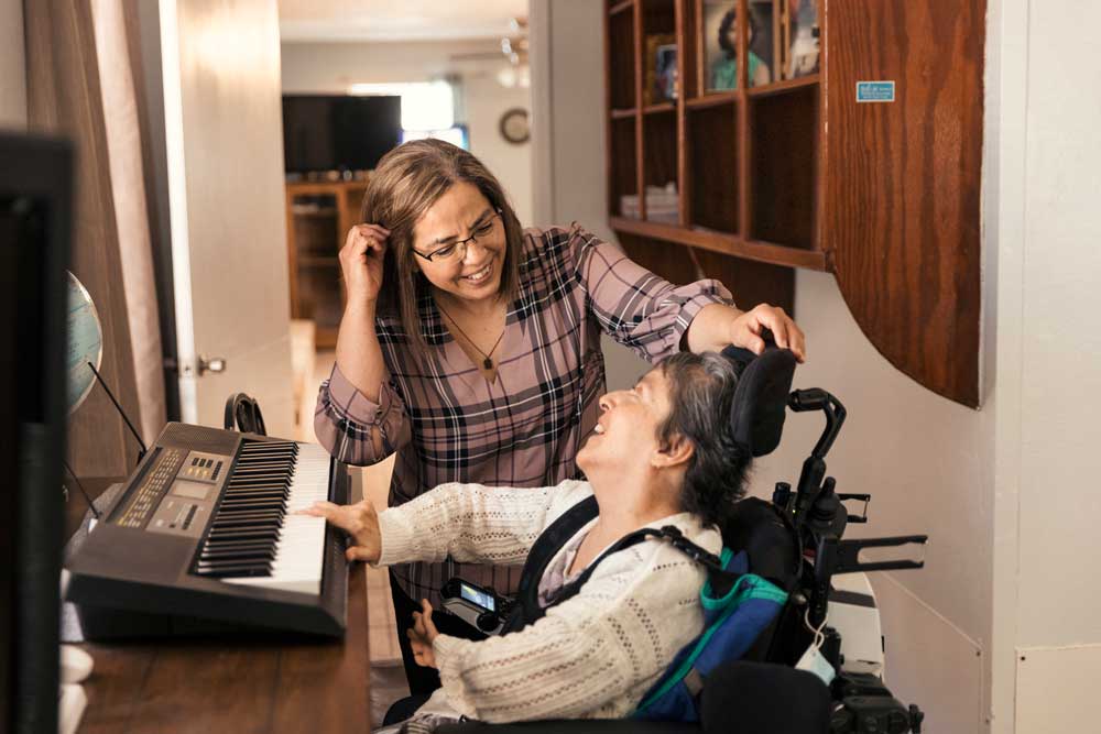 Two people smiling at a home playing an electronic keyboard