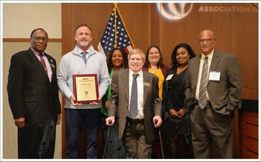 Group photo of 7 people one holding the award plaque.