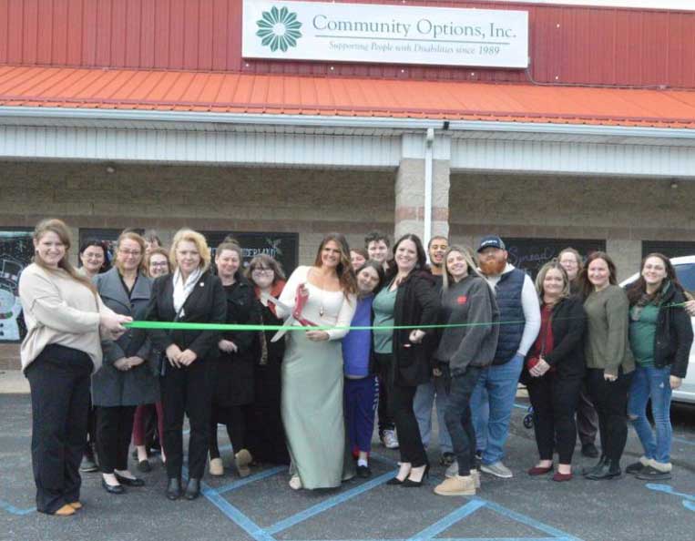 Community Options Inc. Director of Supported Living Ashley Filarski, center, uses a large pair of scissors to cut a ribbon outside of the nonprofit organization’s new administrative office building, 1172 state Route 487, Paxinos, on Dec 12, 2024.