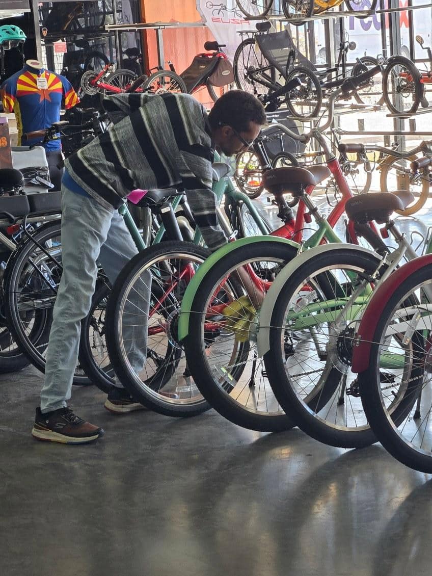Enrique working in the showroom at Ajo Bikes in Tucson, AZ checking on the rear wheel of one of the many bikes on display