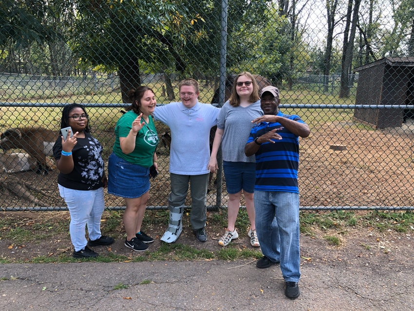 From left to right, Terri Devereaux, Traci Fischer, Andrew Carlson, Clare Brosowsky, David McDougald at Axcel Farm posing for a photo in front of a fenced paddock with animals
