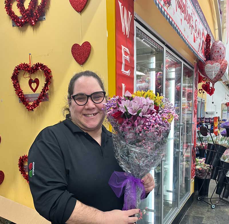 Melissa working at Stop & Shop posing holding a large full bouquet of flowers