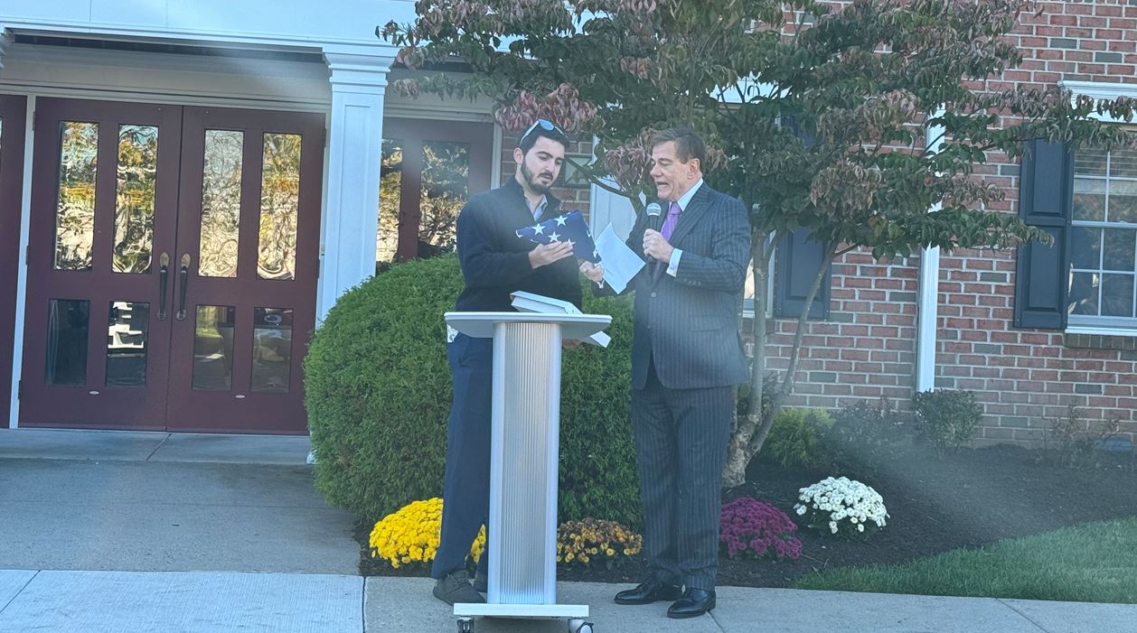 A U.S. flag is presented to Robert Stack by a representative from Congressman Brian Fitzpatrick’s office during a ceremony at the Daily Plan It in Newtown, Pennsylvania.