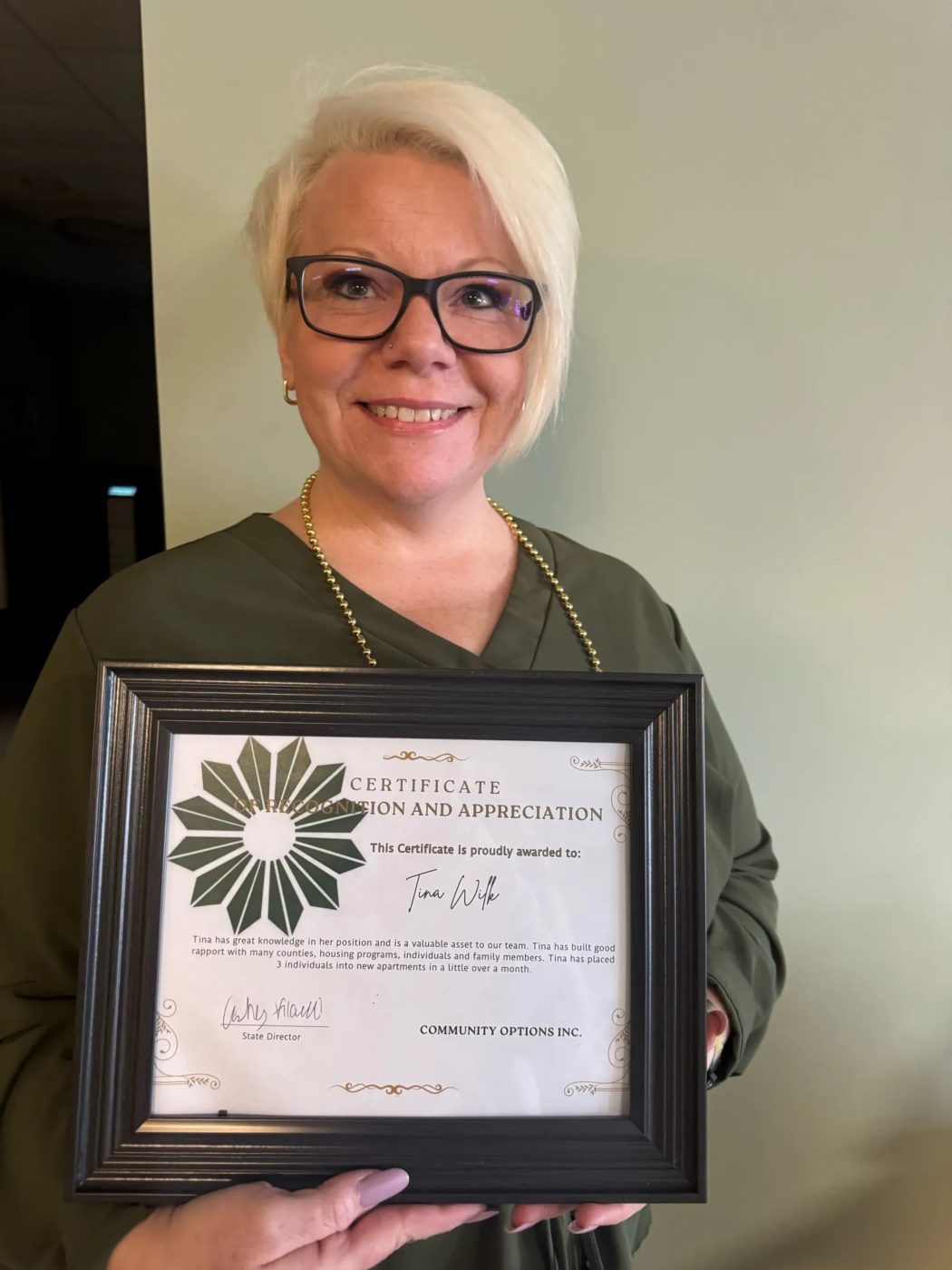 Tina Wilk holding up a framed certificate