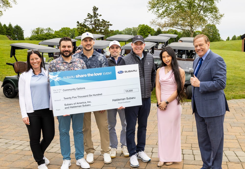 Group holding oversized check reading Subaru share the Love event pay to the order of Community Options Amount Twenty Five Thousand Six Hundred From Subaru of America Inc and Haldeman Subaru proud contributor