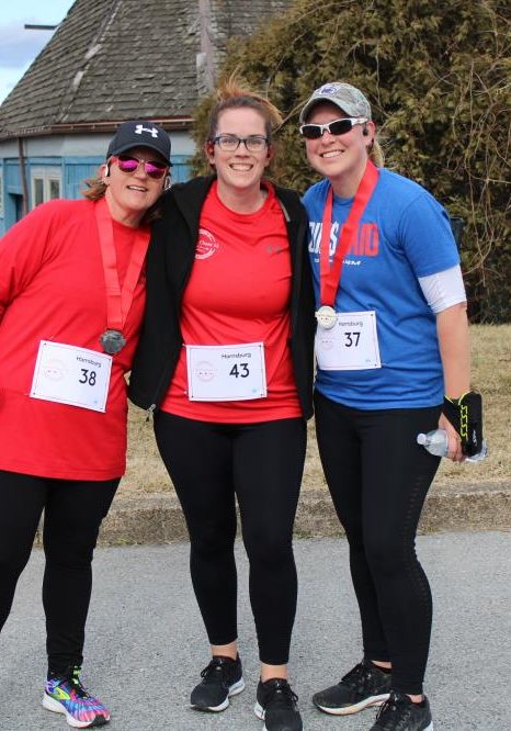 Three People Posing After A Cupids Chase 5k Some Wearing Their Medals Three people posing after a Cupid's Chase 5k some wearing their medals