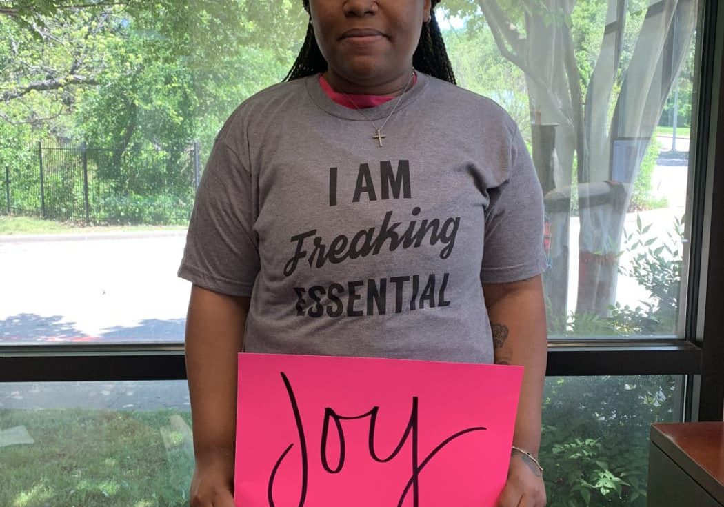 Willisha Ewing holding up a poster that says, "Joy"
